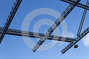 Perforated overhead beams and security camera against a blue sky