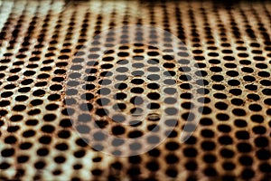 Perforated rusty iron sheet. Surface of industrial mesh with depth of field. Horizontal corrosion grunge background