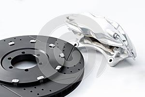 Performance braking system, new silver caliper and new perforated disk. Auto parts on white.