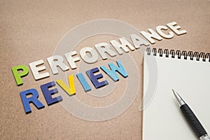 Performance review text with open spiral notebook and pen