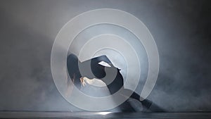 Performed sports girl in dark studio booty dance in silhouette