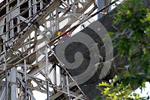 Performing heavy construction work. A worker climbs in height and dismantles large steel elements