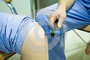 Performing a neurological exam in doctor office. The doctor conducts neurology examination of knee reflex of patient using neurolo