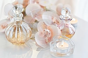 perfume and aromatic oils bottles surrounded by flowers and candles