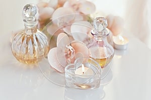 perfume and aromatic oils bottles surrounded by flowers and candles