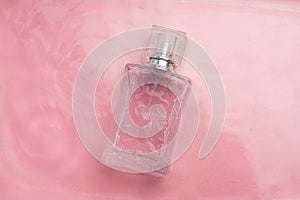 Perfume bottle on the background and water drops. A bottle of perfume without inscriptions . Smell. Perfume on a pink