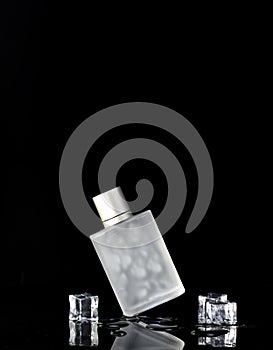 Perfume bottle on a black background with water drops and ice. Minimalistic perfume template