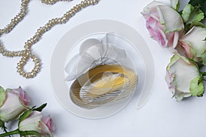 Perfume bottle with flowers and pearl on light background