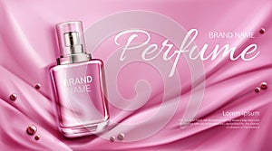 Perfume bottle on folded silk fabric background.