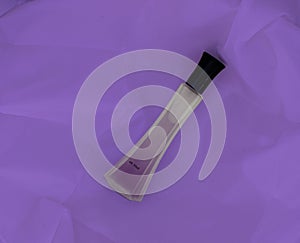 Perfume bottle on lilac fabric background
