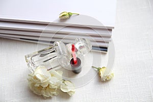 Perfume bottle, red lipstick, white roses and magazines