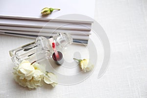 Perfume bottle, red lipstick, white roses and magazines