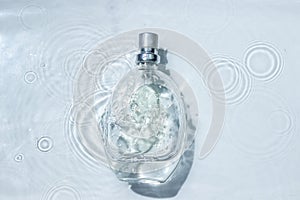 Perfume bottle on the surface of the water. Circle ripples on water surface.