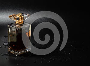 Perfume bottle with water drops on black background