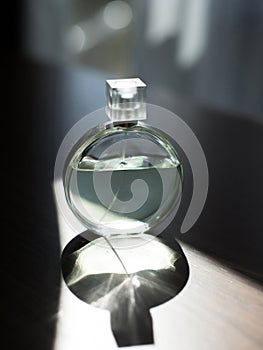 Perfume bottle on a wooden table with shadow