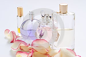 Perfume bottles with flower petals on light background. Perfumery, fragrance collection. Women accessories.