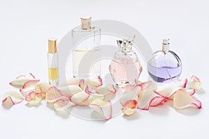 Perfume bottles with flower petals on light background. Perfumery, fragrance collection. Women accessories.