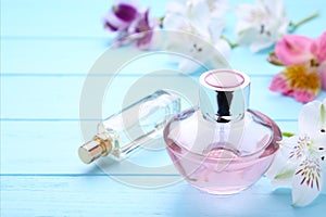 Perfume bottles with flowers on blue background, top view