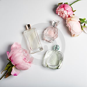 Perfume bottles with flowers on light background. Perfumery, cosmetics, fragrance collection. Flat lay