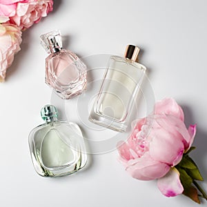 Perfume bottles with flowers on light background. Perfumery, cosmetics, fragrance collection. Flat lay