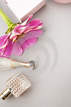 Perfume bottles with pink flower on light background. Perfumery, cosmetics, fragrance collection. Flat lay. Copy space.