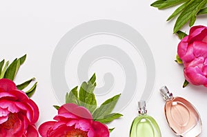 Perfume bottles and pink flowers peonies on light gray background top view Flat lay copy space. Perfumery, cosmetics, female