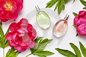 Perfume bottles and pink flowers peonies on light gray background top view Flat lay copy space. Perfumery, cosmetics, female