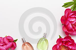 Perfume bottles and pink flowers peonies on light gray background top view Flat lay copy space. Perfumery, cosmetics, female