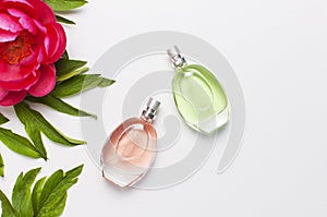 Perfume bottles and pink flowers peonies on light gray background top view Flat lay copy space. Perfumery, cosmetics, female