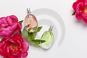 Perfume bottles and pink flowers peonies on light gray background top view Flat lay copy space. Perfumery, cosmetics, female