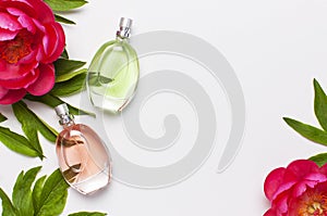 Perfume bottles and pink flowers peonies on light gray background top view Flat lay copy space. Perfumery, cosmetics, female