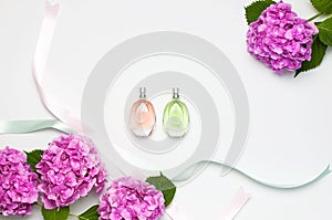 Perfume bottles, pink hydrangea flowers, holiday ribbons on light background top view Flat lay copy space. Perfumery, cosmetics,