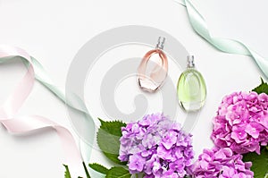 Perfume bottles, pink hydrangea flowers, holiday ribbons on light background top view Flat lay copy space. Perfumery, cosmetics,