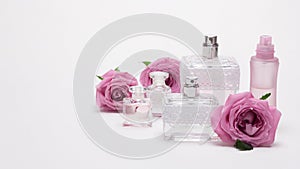 Perfume bottles with rose flowers on light background