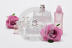 Perfume bottles with rose flowers on light background