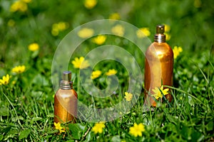 Perfume bottles with yellow flowers on a meadow in spring time