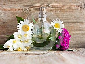 Spa perfume essential aroma oil glass bottle with flower blossoms on old wooden background