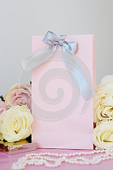 Perfume, gift, pearls, gentle roses on a pink background.