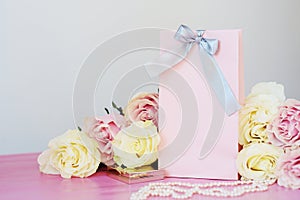 Perfume, gift, pearls, gentle roses on a pink background.