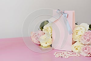 Perfume, gift, pearls, gentle roses on a pink background.