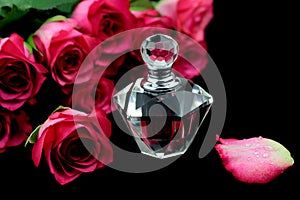 Perfume and roses on black background