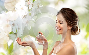Happy woman with perfume over cherry blossoms
