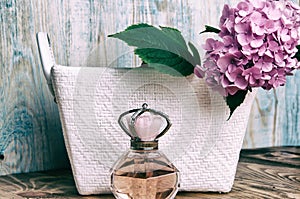 Perfumes and hydrangea in a white basket on blue wooden background