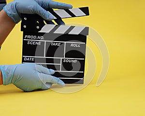 During the period of pandemics, hands in gloves concept of the film industry, a minimalistic composition on a yellow