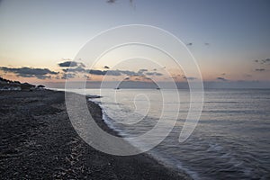 Perivolos beach on Santorini island in Greece at sunrise. The background is a blue sky with white clouds