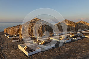 Perivolos beach on Santorini island in Greece at sunrise. The background is a blue sky with white clouds