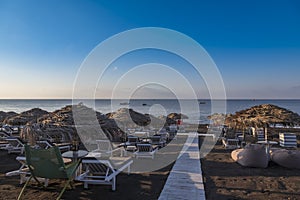 Perivolos beach on Santorini island in Greece at sunrise. The background is a blue sky with white clouds