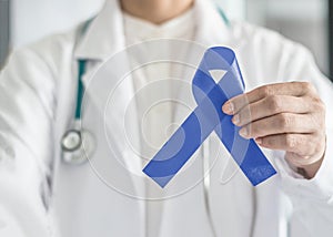 Periwinkle blue ribbon awareness with color bow on medical doctor`s hand for stomach and small intestine cancer, esophageal cancer