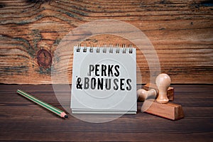 PERKS AND BONUSES. Cardboard notepad on wooden texture table