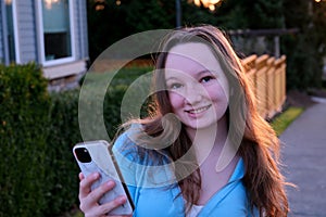 Perky female teenager texting in the park with smart phone